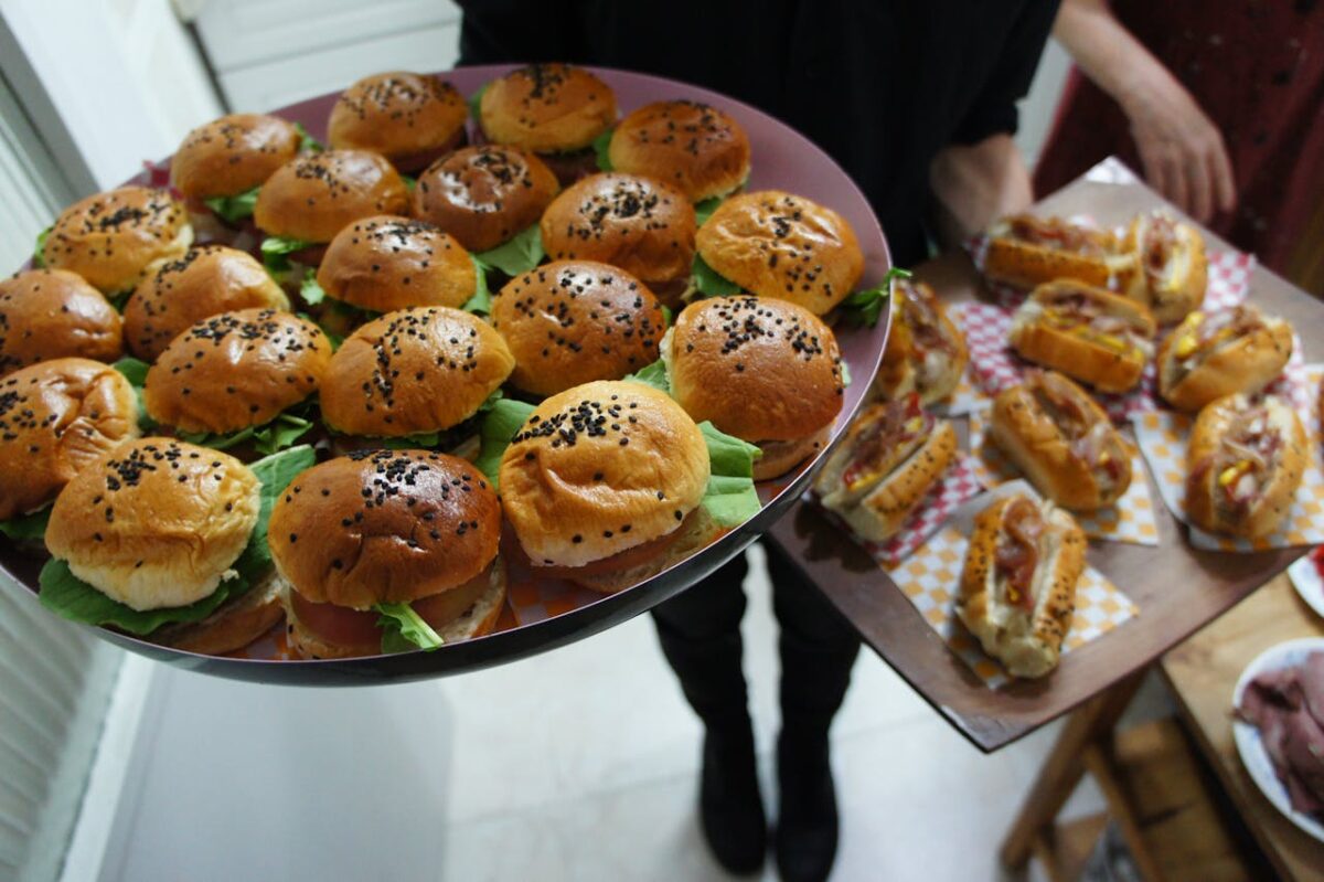 Close-up of trays with assorted mini burgers and hot dogs perfect for parties.