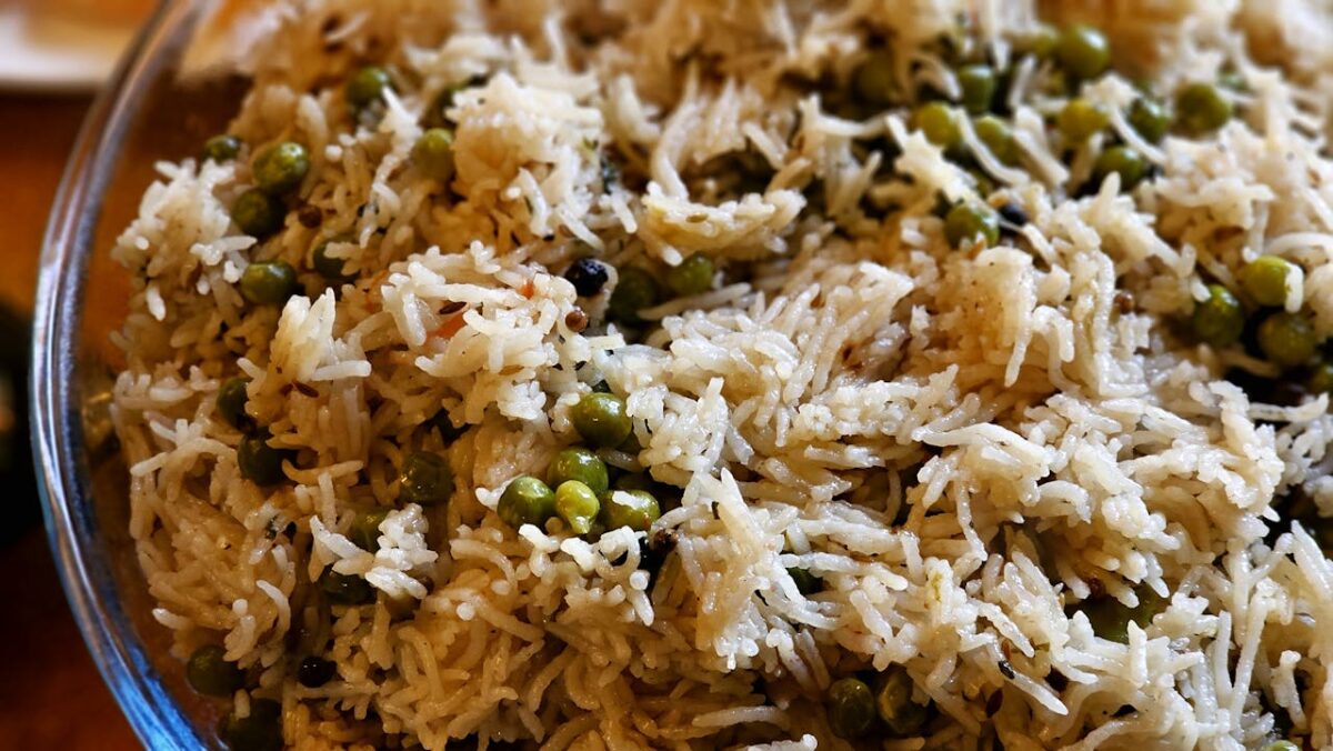 A delicious serving of basmati rice with green peas in a glass bowl, perfect for a flavorful meal.